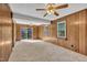 Carpeted living room with wood paneling, windows, and a sliding glass door at 2608 Foxgate Dr, Raleigh, NC 27610
