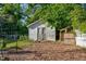 Backyard shed featuring wood siding and door, surrounded by trees and foliage at 302 Villa St, Rocky Mount, NC 27804