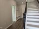 Bright foyer features wood flooring, staircase with dark handrail and access to hall with coat storage bench at 3026 Freewinds Way # 50, Cary, NC 27519