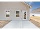 View of the home's back exterior with patio, a sliding glass door, windows, and pale yellow siding at 322 Deodora Ln, Cameron, NC 28326