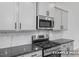 Close-up of the kitchen's stainless gas range, microwave, gray cabinets and dark granite counters at 3918 Well Fleet Dr, Fuquay Varina, NC 27526