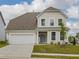 Charming two-story home with a well-manicured lawn, attached garage, and inviting light blue front door at 392 Peach Grove Way, Lillington, NC 27546