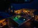 An aerial view of the home, showing the back patio with outdoor furniture, pool and spa at night at 403 Granville Rd, Chapel Hill, NC 27514
