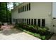 Side view of the house showcasing multiple windows and manicured shrubs with a large concrete patio at 4113 Oak Park Rd, Raleigh, NC 27612