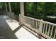 Close-up of the front porch railing and tiled flooring with lush greenery in the background at 4113 Oak Park Rd, Raleigh, NC 27612