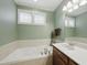 Bathroom with white tiled tub, single sink, and soft green wall paint at 420 Marsh Landing Dr, Holly Springs, NC 27540