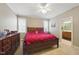 Cozy main bedroom featuring a red comforter, two windows, and an attached bathroom at 420 Marsh Landing Dr, Holly Springs, NC 27540