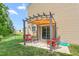 Inviting backyard patio with pergola, red seating, and lush green grass, ideal for outdoor relaxation at 4221 Northrop Dr, Haw River, NC 27258