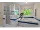 Well-lit bathroom with a soaking tub, glass-enclosed shower, and a view of the lush green trees outside at 524 Preston Andrews Rd, Bahama, NC 27503