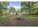 A spacious backyard with a brick fire pit and beautiful trees and greenery at 5300 Whippoorwill St, Durham, NC 27704
