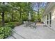 An outdoor patio space with a table, chairs, and an umbrella surrounded by beautiful trees and greenery at 5300 Whippoorwill St, Durham, NC 27704