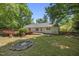 Charming backyard featuring a deck, fire pit, and partially fenced yard, all surrounded by lush trees at 556 Margaret Pl, Garner, NC 27529
