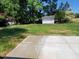 Large backyard featuring a concrete patio and a white storage shed surrounded by mature trees at 5718 Woodcrest Dr, Raleigh, NC 27603