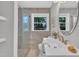 Bright bathroom featuring double sinks, gray ceramic tiles, and a frameless glass shower at 5718 Woodcrest Dr, Raleigh, NC 27603