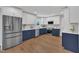 Well-lit kitchen featuring two-tone cabinetry, stainless steel appliances, quartz countertops, and vinyl plank flooring at 5718 Woodcrest Dr, Raleigh, NC 27603