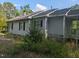View of the side exterior with siding, windows, and overgrown foliage at 630 Sunnybrook Rd, Raleigh, NC 27610