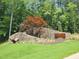 View of Shinleaf Estates entrance with stone wall, signage, and mature trees, creating a welcoming atmosphere at 7652 Falls Creek Ln, Raleigh, NC 27614