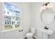 Well-lit powder room featuring a pedestal sink and a round mirror at 808 Hillfarm Dr, Wake Forest, NC 27587