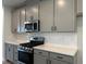 Modern kitchen with stainless steel appliances, gray cabinetry, and quartz countertops at 808 Hillfarm Dr, Wake Forest, NC 27587