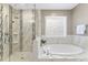 Modern bathroom featuring a glass-enclosed shower and a soaking tub with marble surround at 1005 Collins Dr, Raleigh, NC 27609