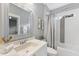 Bright bathroom features a decorative mirror, white vanity, and shower with gray patterned tile accent at 1005 Collins Dr, Raleigh, NC 27609
