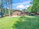 Large backyard features a brick home with wooden deck, mature trees and lush green lawn at 1103 Brucemont Dr, Garner, NC 27529