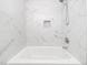 Bright bathroom features modern shower head over tub with marbled tile surround and a small inset shelf for storage at 1103 Brucemont Dr, Garner, NC 27529