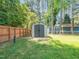 Well-maintained storage shed in a fenced backyard with lush green grass and mature trees at 1103 Brucemont Dr, Garner, NC 27529