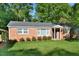 Charming brick home featuring manicured lawn with bushes, a covered porch, and classic architectural details at 114 Short E St, Hillsborough, NC 27278