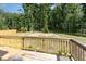 View of a backyard deck with wood railings, surrounded by lush trees at 115 Parkers Gate Dr, Youngsville, NC 27596