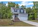 View of home with gray siding, white trim, black shutters, brick stairs, green lawn, and tree-lined background at 115 Parkers Gate Dr, Youngsville, NC 27596