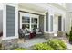 Inviting front porch with cozy seating, decorative cushions, and stone pillar accents at 1211 Brown Velvet Ln, Apex, NC 27523