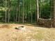Beautiful backyard fire pit area surrounded by a canopy of lush green trees and stacked firewood at 128 Madison Ct, Siler City, NC 27344