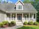 Welcoming front porch with white railings, hanging plants, landscaping and a walkway to the front door at 128 Madison Ct, Siler City, NC 27344