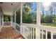 Relaxing porch with wooden floors, a porch swing, white railing, and a view of the surrounding greenery at 128 Madison Ct, Siler City, NC 27344