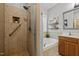 Tiled shower with built-in niche, safety bar, and glass door next to vanity and soaking tub at 128 Madison Ct, Siler City, NC 27344