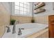 Close up of the soaking tub featuring stylish fixtures and wall shelving and a large window at 128 Madison Ct, Siler City, NC 27344