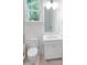 Well-lit bathroom featuring a white vanity, toilet, and window with natural light at 1444 Old Apex Rd, Cary, NC 27513