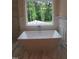 Modern bathroom featuring a freestanding tub beneath a bright window with lush forest views at 1444 Old Apex Rd, Cary, NC 27513