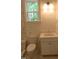 Bright bathroom featuring a white vanity, toilet, and a large window offering natural light and a view of the outdoors at 1444 Old Apex Rd, Cary, NC 27513