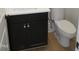 A compact bathroom featuring a black vanity cabinet with white countertop and a standard toilet maximizing limited space at 1444 Old Apex Rd, Cary, NC 27513