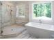 Modern bathroom featuring a luxurious soaking tub, glass-enclosed shower, and a window at 1444 Old Apex Rd, Cary, NC 27513