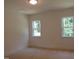 A bright bedroom with neutral walls, carpet flooring, and windows overlooking lush greenery at 1444 Old Apex Rd, Cary, NC 27513