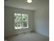 A bright bedroom with neutral walls, carpet flooring, and windows overlooking lush greenery at 1444 Old Apex Rd, Cary, NC 27513