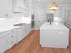 Open kitchen with an island, stainless steel appliances, white cabinetry, and hardwood flooring at 1444 Old Apex Rd, Cary, NC 27513