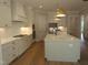 A contemporary kitchen with white cabinets, stainless steel appliances, and modern lighting fixtures offers a sleek and functional space at 1444 Old Apex Rd, Cary, NC 27513