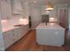 Bright kitchen with white cabinets, stainless steel appliances, quartz countertops, and a large island with pendant lights at 1444 Old Apex Rd, Cary, NC 27513