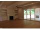 Bright living room featuring hardwood floors, fireplace, built-in shelving, ceiling fan and sliding glass doors at 1444 Old Apex Rd, Cary, NC 27513