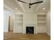 Living room with hardwood flooring, fireplace with tile surround, built-in shelving and modern ceiling fan at 1444 Old Apex Rd, Cary, NC 27513