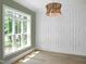 Bright living room featuring a decorative light fixture, trim accent wall, and large window at 1444 Old Apex Rd, Cary, NC 27513
